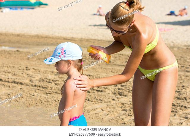 Mom on the beach gets a little girl back on sunscreen
