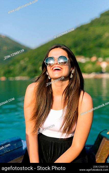 Woman with sunglassess enjoying the sunny day on a boat on a lake