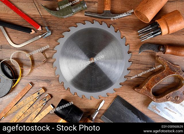 High angle closeup of a large group of tools arranged around a round table saw blade
