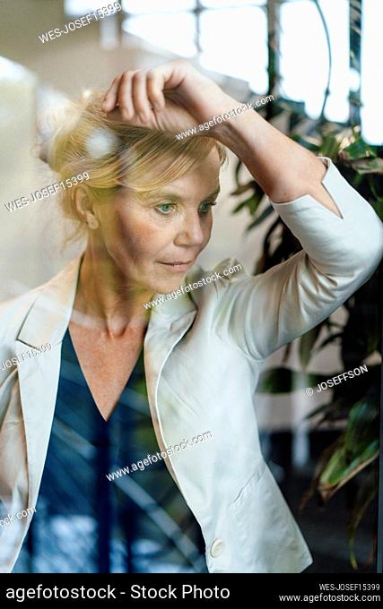 Thoughtful businesswoman leaning on glass
