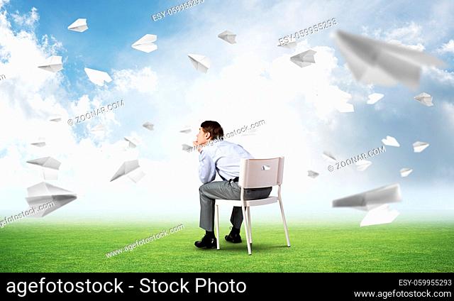 young businessman sits on an office chair, thoughtful and looking up