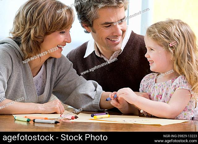 Parents helping their daughter draw