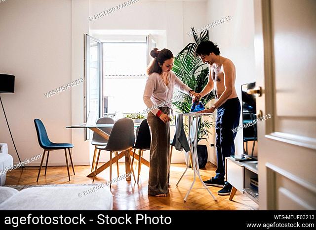Woman helping man ironing at home