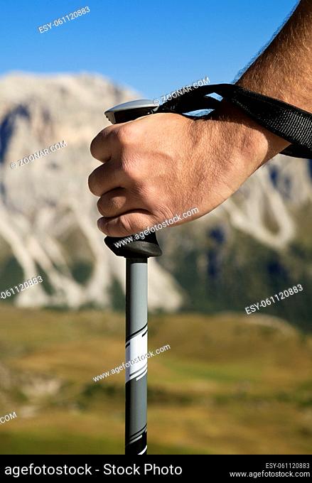 Close-up of a hand with walking pole against mountain in the distance
