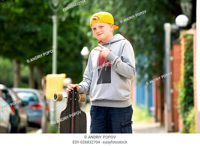 Portrait Of A Boy With Skateboard Making Peace Sign