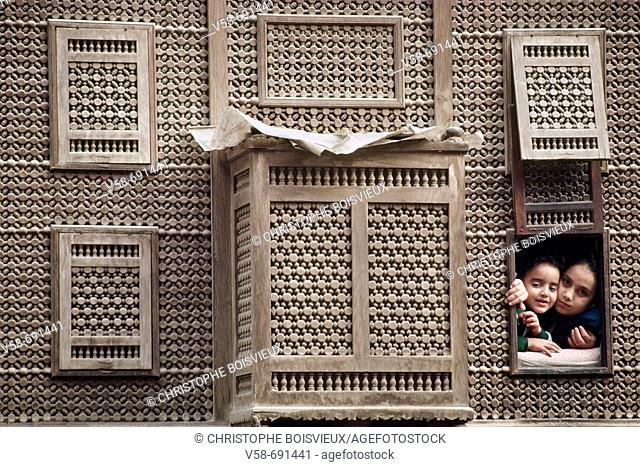 Children watching the street life from a 'mashrabiya' window in Old Cairo. Egypt