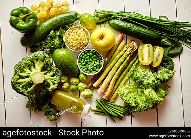 Healthy concept with green antioxidant organic vegetables, fruits and herbs and bottle of fresh smoothie. Placed on white wooden table