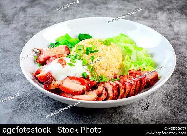 Barbecued red pork and crispy pork in red sauce, served with rice and vegetable on white plate