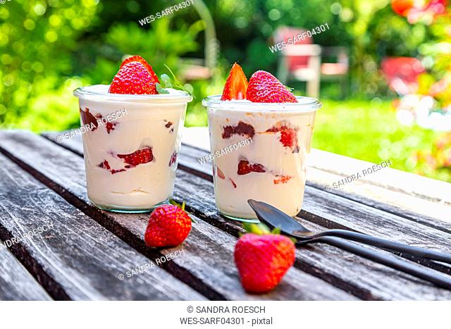 Yogurt with fresh strawberries and mint on wood