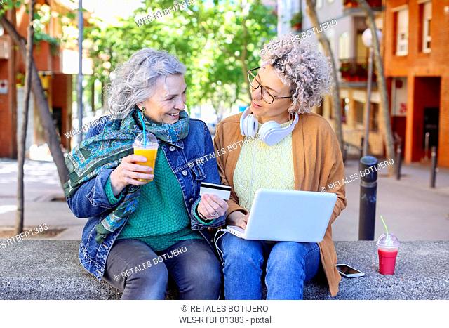 Senior mother with her adult daughter shopping online together in the city
