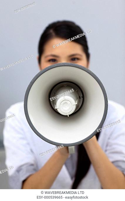 Young businesswoman shouting instructions through a megaphone