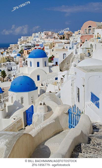 White buildings with steep slope with blue dome churches on mountain in Fira in Santorini Greece in Greek Islands