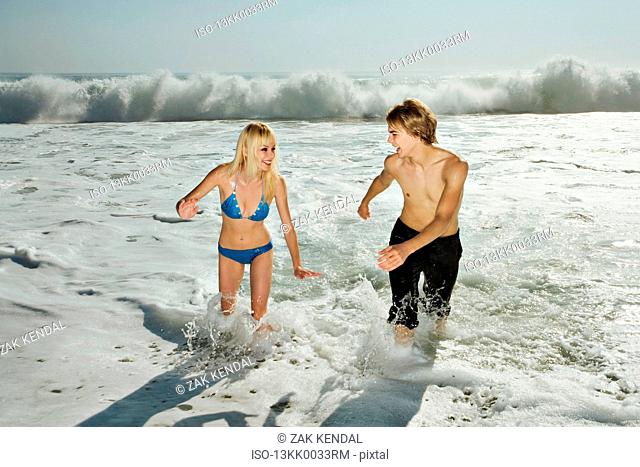 Couple, laughing, running from waves
