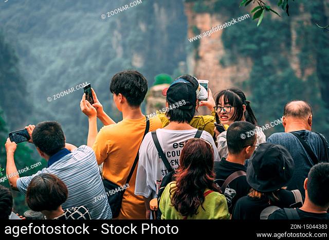 Zhangjiajie, China - August 2019 : Tourists taking pictures on mobile phones on the viewpoint in Tianzi mountain range, Avatar mountains nature park