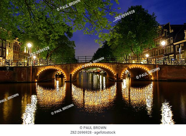 Illuminated canal bridge at night on the canal between Prinsengracht and Brouwersgracht in Amsterdam, Holland