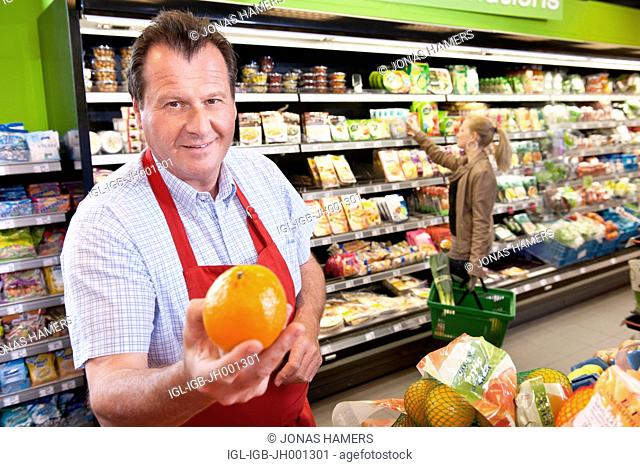 A supermarket employee arranges goods and food