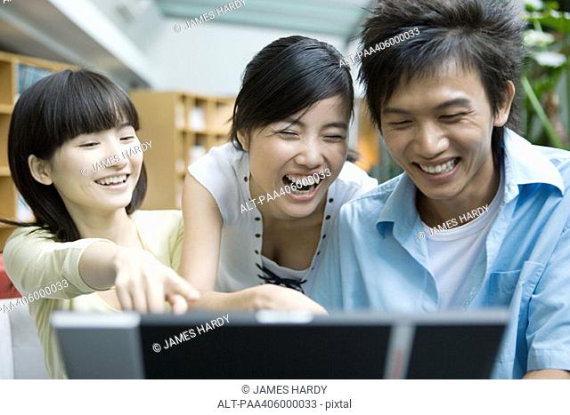 Three friends using computer, laughing