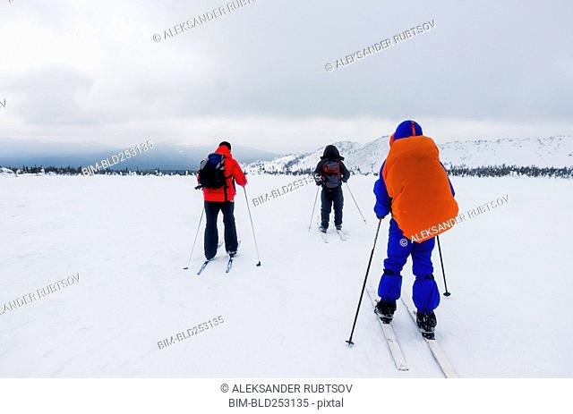 Caucasian people cross-country skiing in field