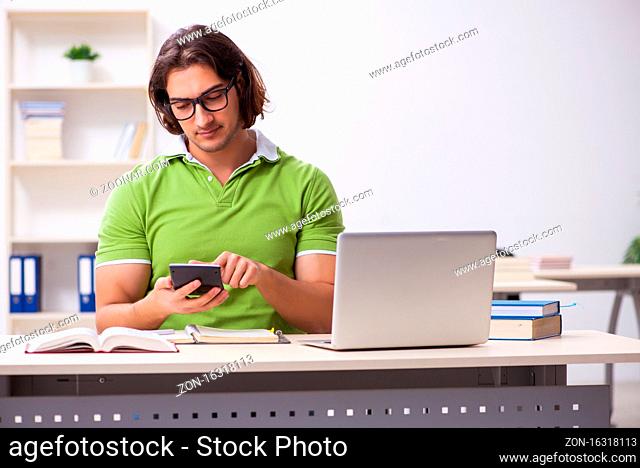 Young male student in the classroom studying
