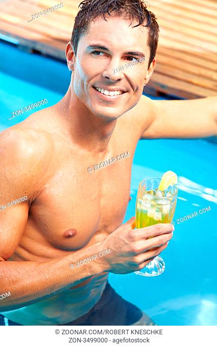 Junger attraktiver Mann mit einem Cocktail im Pool