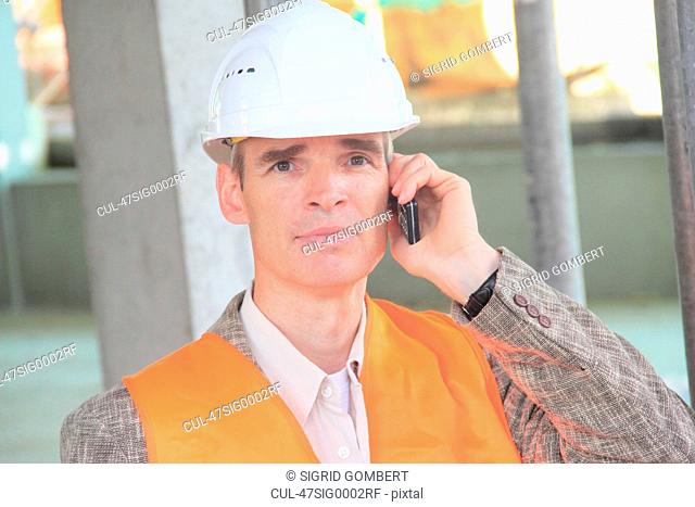 Businessman in hard hat on cell phone