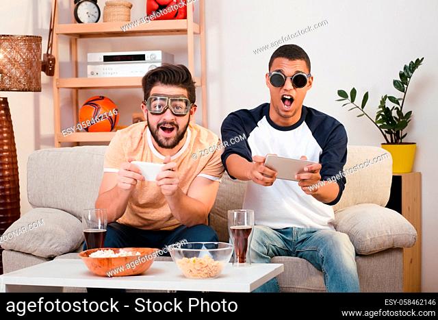 Picture of happy best friends playing computer games with special glasses on. Handsome men spending free time or weekends all together at home