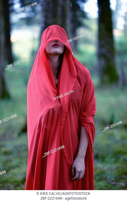 Hispanic woman with a red cloak, recreating a modern fairy tale of Little Red Riding Hood