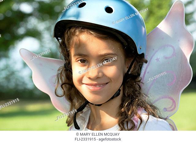 Portrait of young girl wearing a bike helmet and fairy wings;Whitby ontario canada