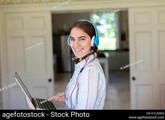 Portrait confident teenage girl with headphones and laptop