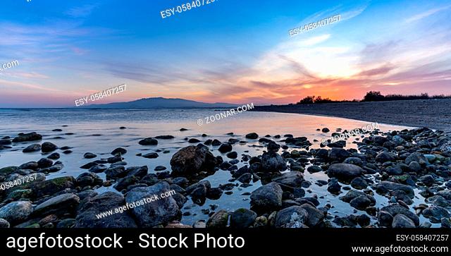 A colorful sunset on the Mediterranean Sea in Almeria with rocks and tidal pools in the foreground