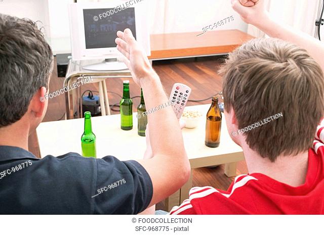 Two football fans watching football match on TV