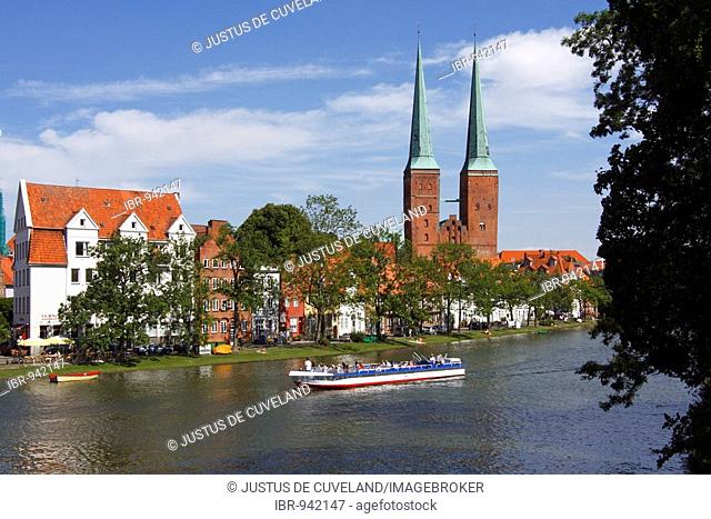 Pleasure boat on the Trave river, Luebeck cathedral, cathedral in the old hanseatic city of Luebeck and the An der Obertrave street