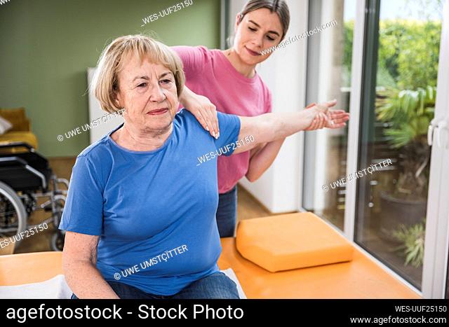 Physiotherapist massaging disabled woman's hand on table