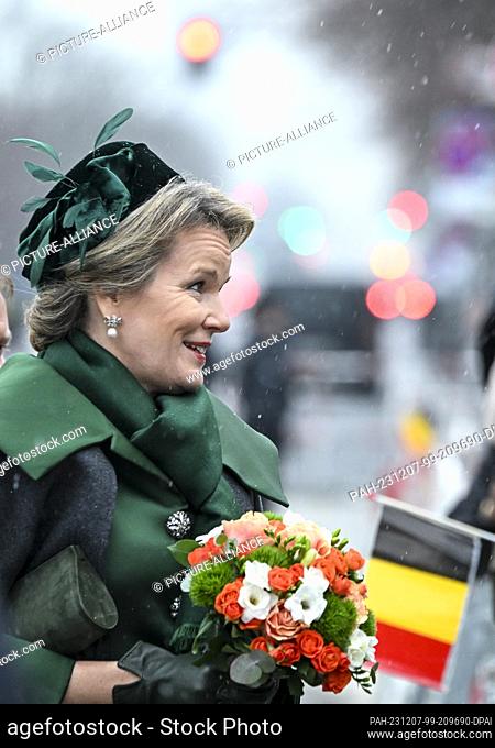 05 diciembre 2023, Berlín: La reina Mathilde de Bélgica con un ramo de flores en sus manos es saludada por espectadores esperando con banderas belgas en la...