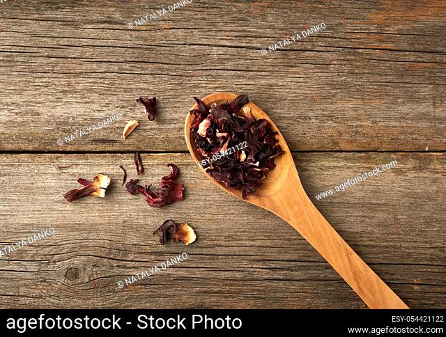 dry petals of red hibiscus in a wooden spoon, tea preparation, top view