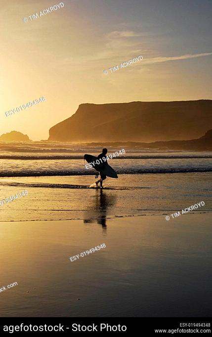 Sufer at sunset in Polzeath, Cornwall