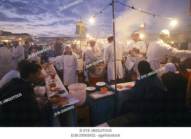 Djemaa el Fna. Food vendors serving up food to hungry customers seated around them at dusk
