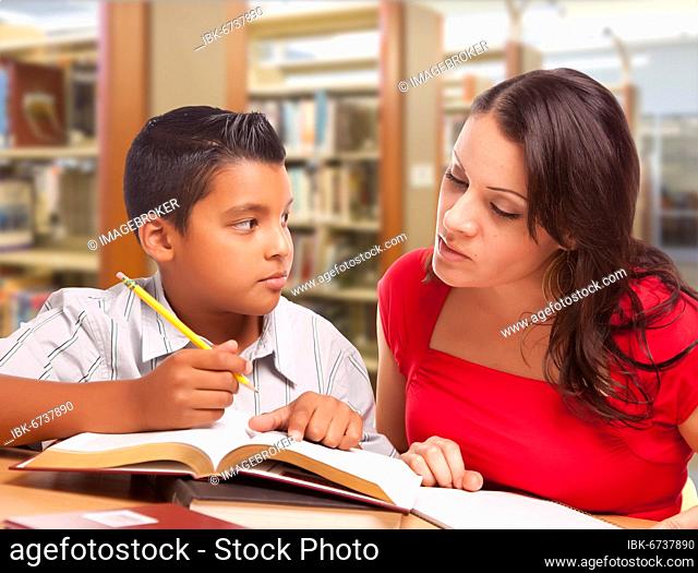 Hispanic mother and son studying inside the library
