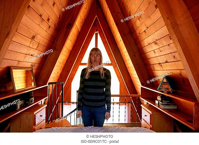 Woman making face in bedroom in A-frame house