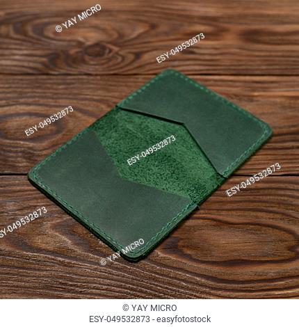Handmade green emerald leather cardholder on wooden background. Stock photo with blurred background