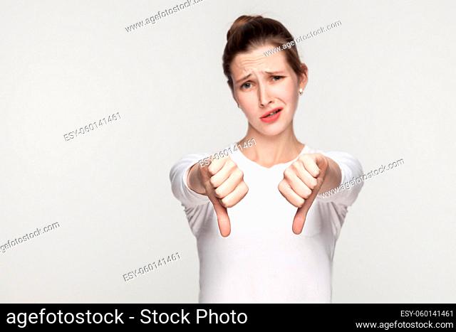 Unhappy woman demonstrate dislike sign. Studio shot, gray background