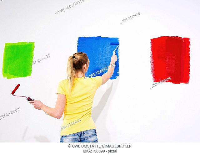Young woman painting a wall with paint samples