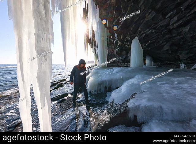RUSSIA, VLADIVOSTOK - DECEMBER 4, 2023: A tourist stands by a rock covered with icicles in Bogdanovicha Bay of Russky Island. Yuri Smityuk/TASS