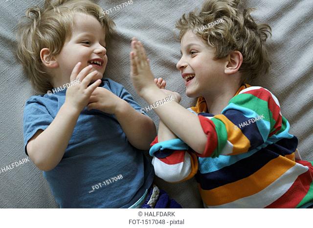 High angle view of happy siblings playing on bed at home