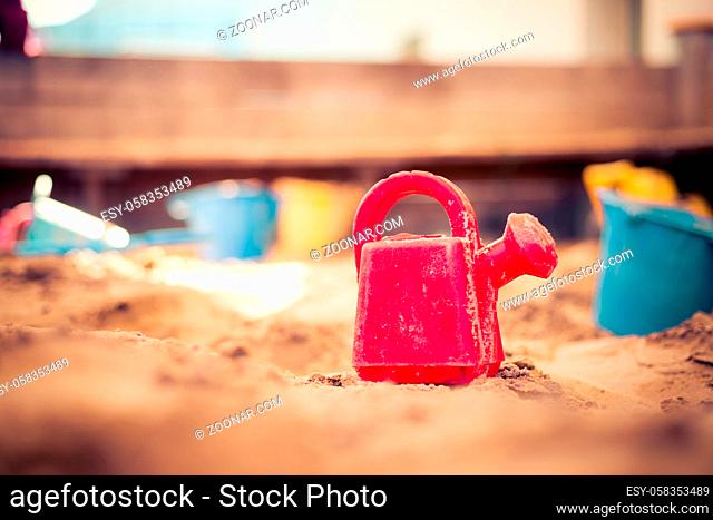 Children plastic toys in the sand box. Watering can, selective focus