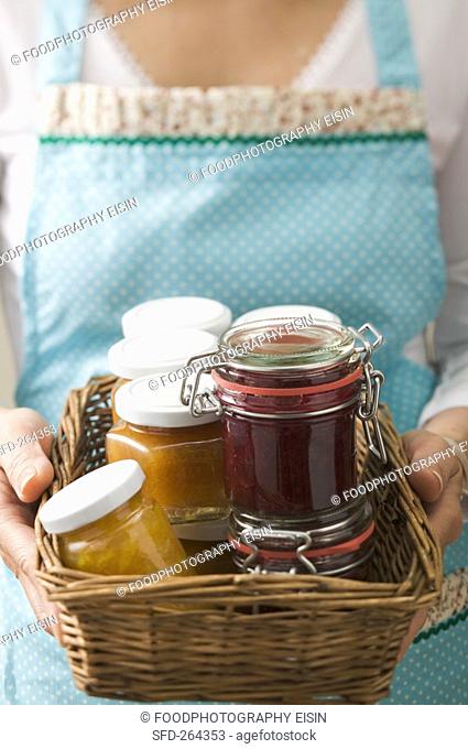 Woman holding a basket full of jars of jam