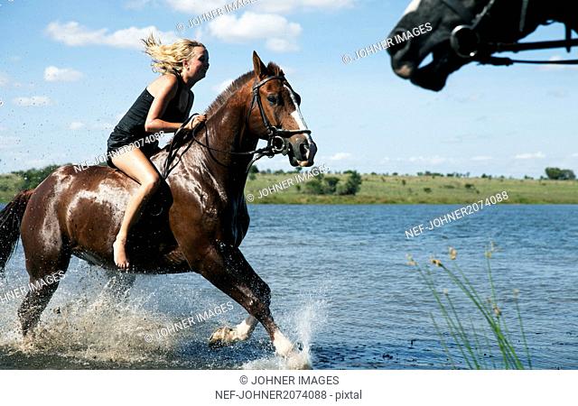 Woman riding horse across river