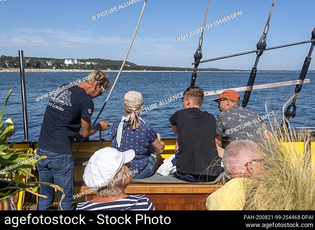 17 August 2020, Mecklenburg-Western Pomerania, Binz: Passengers on the Loth Loriën watch a crew member attach a line. The three-master sails under Dutch flag