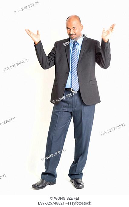 Portrait of full body mature Indian business man open arms as like showing something, standing on plain background