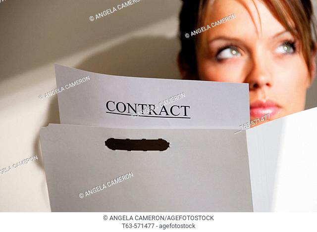 20 yr old young woman holding file/ contract papers looking up